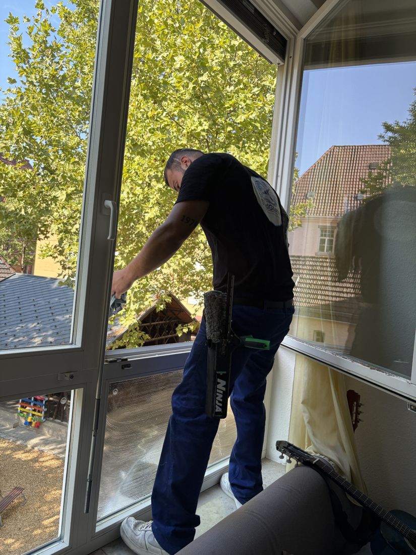 SüdGlanz-Mitarbeiter reinigt ein großes Fenster von innen